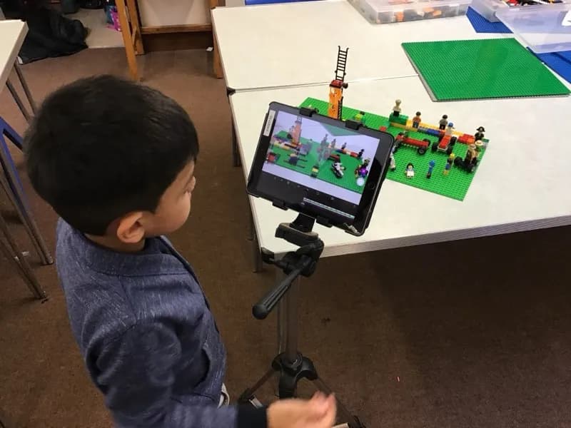 A child filming a LEGO scene for a stop-motion animation on an iPad