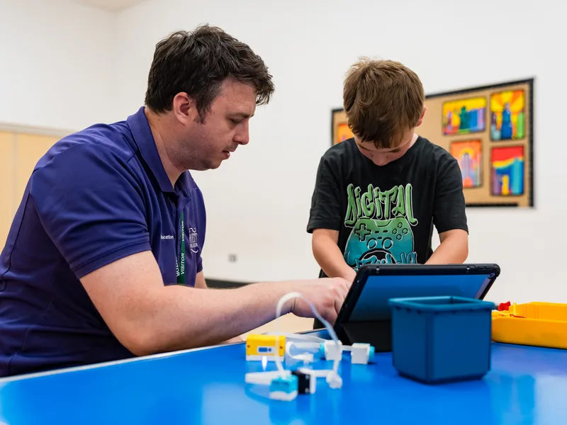 An instructor helping a child with an iPad and a LEGO build